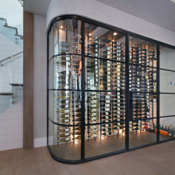Curved Euroline Steel Windows and Doors wine room doors showcasing a comprehensive wine collection.