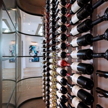 Close-up of wine bottles behind curved Euroline Steel Windows and Doors wine room doors.