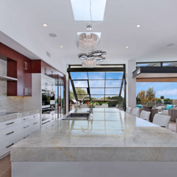 Luxurious kitchen with Euroline Steel Windows and Doors specialty doors opening to a patio.