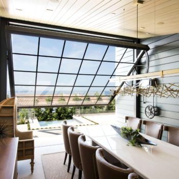Euroline Steel Windows and Doors specialty doors framing a panoramic view from a stylish dining area.