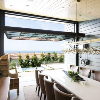 Modern dining space under Euroline Steel Windows and Doors specialty glass ceiling, overlooking pool.