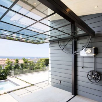Modern dining space under Euroline Steel Windows and Doors specialty glass ceiling, overlooking pool.