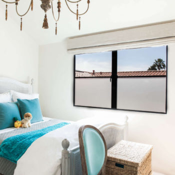 Cozy and inviting bedroom enhanced by Euroline Steel Casement Windows, featuring a large black steel-framed window that provides a clear view of palm trees and a serene outdoor environment. The room is decorated with a comfortable bed, vibrant blue accents, and vintage-style furniture, creating a charming and relaxing space.