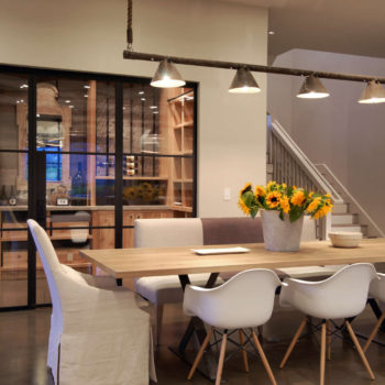 Dining area with Euroline Steel Windows and Doors specialty doors viewing into a wine room.